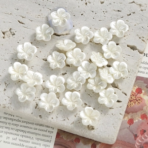 11mm pearlescent white orchid nail art flower charms on a textured stone display board