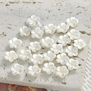 Macro detail of pearlescent white resin plum blossom charms for nail art DIY designs