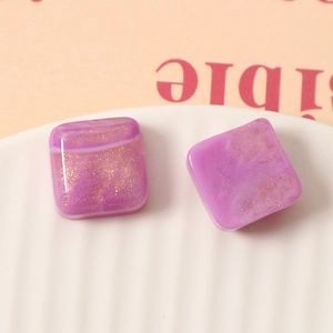 Detail of 16mm square resin charms with purple smoke texture and gold glitter for DIY crafts