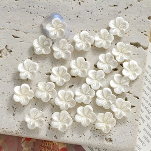 Detailed view of pearlescent white orchid nail charms on a soft purple manicure base