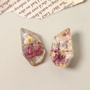 Close-up of resin charms with dried flowers, pearls, and gold foil for DIY jewelry