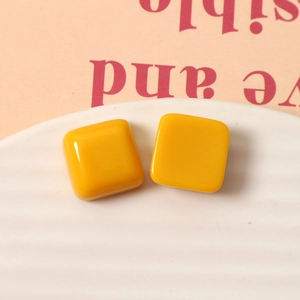 Macro view of 15mm bright yellow square resin stud earrings with glossy ceramic glaze finish