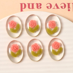 Macro detail of 6pcs oval resin charms with 3D pink roses and green leaves for DIY