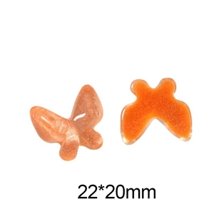 Macro view of 22x20mm orange glitter resin butterfly charms for DIY jewelry making