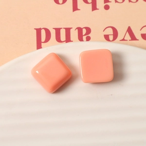 Macro shot of 15mm square peach pink resin charms with polished glossy finish