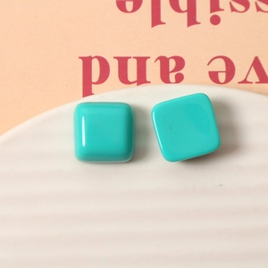 Glossy green square resin studs displayed on a textured ceramic plate for DIY accessories