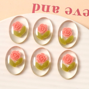 Detailed macro view of 6 oval resin DIY charms with pink roses and green leaves