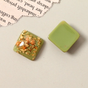 Macro view of square resin accessories with gold foil and dried flowers for jewelry