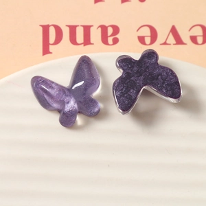 Detail of purple glitter and marble texture resin butterfly charms on white tray