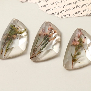 Macro shot of faceted resin charms with embedded dried flowers for DIY jewelry making