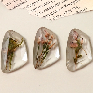 Macro shot of clear faceted resin charms with purple dried flowers for DIY jewelry making