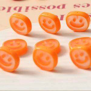 Macro detail of orange translucent resin smiley face beads for DIY jewelry making