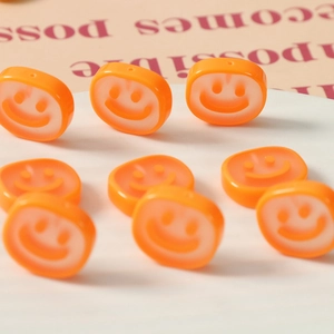 Macro shot of bright orange resin smiley face charms for DIY jewelry and hair accessories