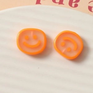 Macro detail of translucent orange resin charms with smiley faces for DIY jewelry crafts