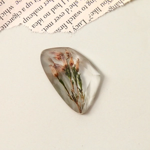 Detailed view of faceted resin pendant with embedded real dried flowers for DIY jewelry