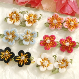 Macro detail of handmade embroidered felt flowers with faux pearl center and soft texture