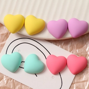 Macro-opname van matte hartvormige DIY bedeltjes in pastelgeel, paars, groen en roze kleuren