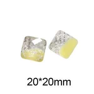 Detail view of square resin charms with seashell fragments and vintage newsprint inserts