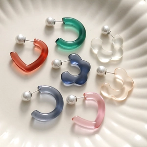 Translucent resin flower earrings with pearls in various colors on a ceramic tray