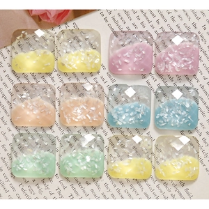 Macro shot of square resin DIY charms with glitter and macaron colors on book page