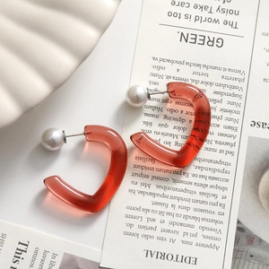 Detail of amber resin heart-shaped hoop earrings with pearls on a ceramic plate