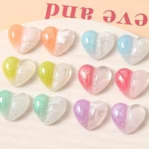 Macro shot of 12 heart-shaped resin charms in mixed pastel macaron colors with glitter