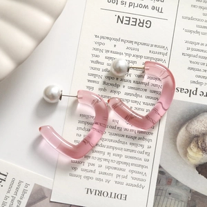 Detail of pink transparent heart earrings with white pearls on a shell tray