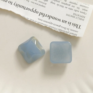 Detail of light blue square resin charms with gold glitter texture for DIY jewelry making