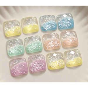 Macro shot of colorful square faceted resin charms with embedded iridescent shells for DIY craft