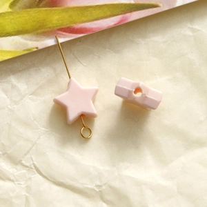 Macro view of 10mm light pink star-shaped acrylic beads with pre-drilled holes for DIY crafts