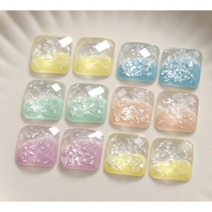 Macro detail of 12 faceted resin square charms with white shell flakes and pastel colors