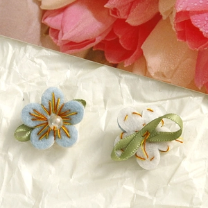 Close-up of handmade blue fabric flower with pearl center and felt backing for DIY crafts
