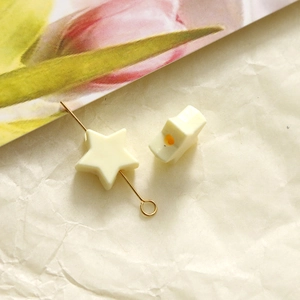 Macro shot of a cream acrylic star bead with gold metal pin for jewelry making