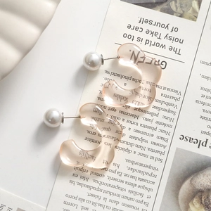Detail of pink translucent resin C-shaped flower earrings with white pearl accents