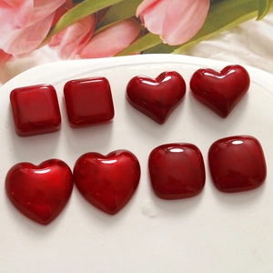 Macro shot of red heart resin cabochons on white ceramic plate for DIY jewelry making