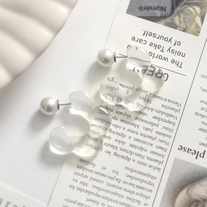 Detailed view of translucent wave-shaped resin earrings with elegant faux pearl backing