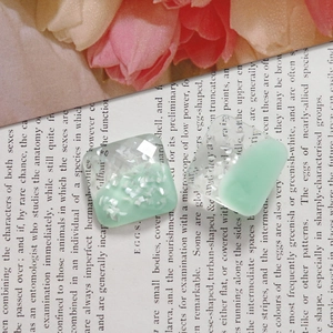 Close-up of faceted square resin charms in mint green and transparent glitter finish
