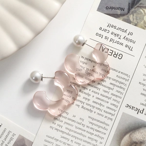 Detailed macro view of pink translucent resin flower earrings with large white pearl studs