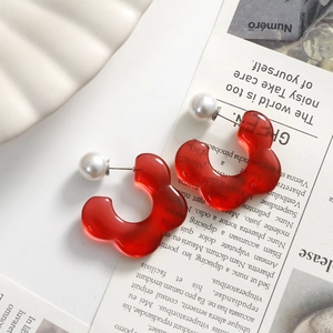 Detail of red translucent resin flower earrings with imitation pearl studs on magazine