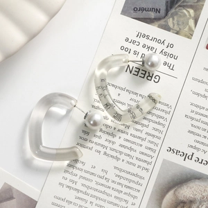 Detail of heart resin earring with black calligraphy and white pearl backing on magazine