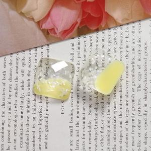 Macro shot of square resin earring charms with crushed shell inlay and warm yellow tones