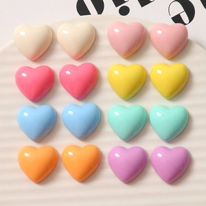 Flat lay of colorful heart resin charms in eight colors on a white ceramic tray
