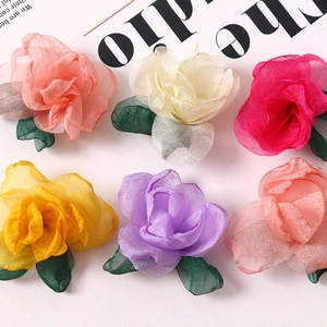 Detail of multi-layered chiffon flower heads in various colors with green fabric leaves