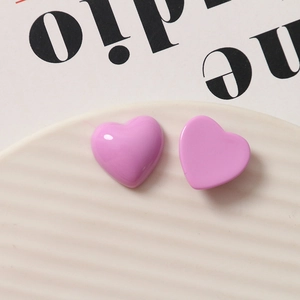 Lavender purple heart-shaped resin charms displayed on a white ceramic wavy tray