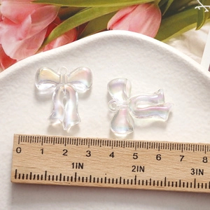 Macro shot of iridescent resin bow charms for DIY jewelry making on white tray