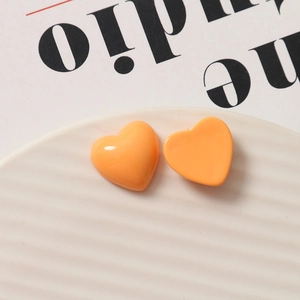 Close-up of gloss finish orange resin heart charms on a white ceramic plate