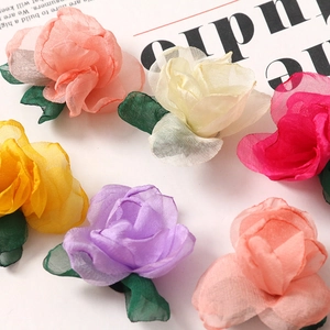 Flat lay of colorful handmade chiffon rose petals with green leaves for DIY hair accessories