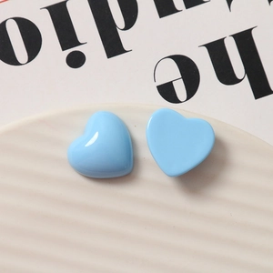 Glossy sky blue heart-shaped resin accessory on a white wavy ceramic dish