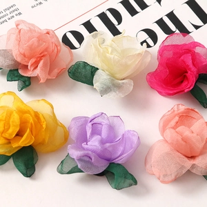 Detailed macro view of layered sheer gauze rose petals with green fabric leaves for DIY