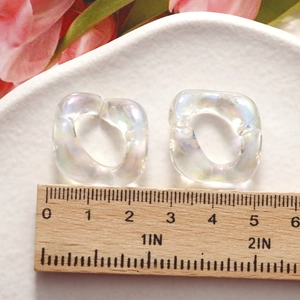 Iridescent acrylic flower resin beads for jewelry making shown on a white ceramic plate